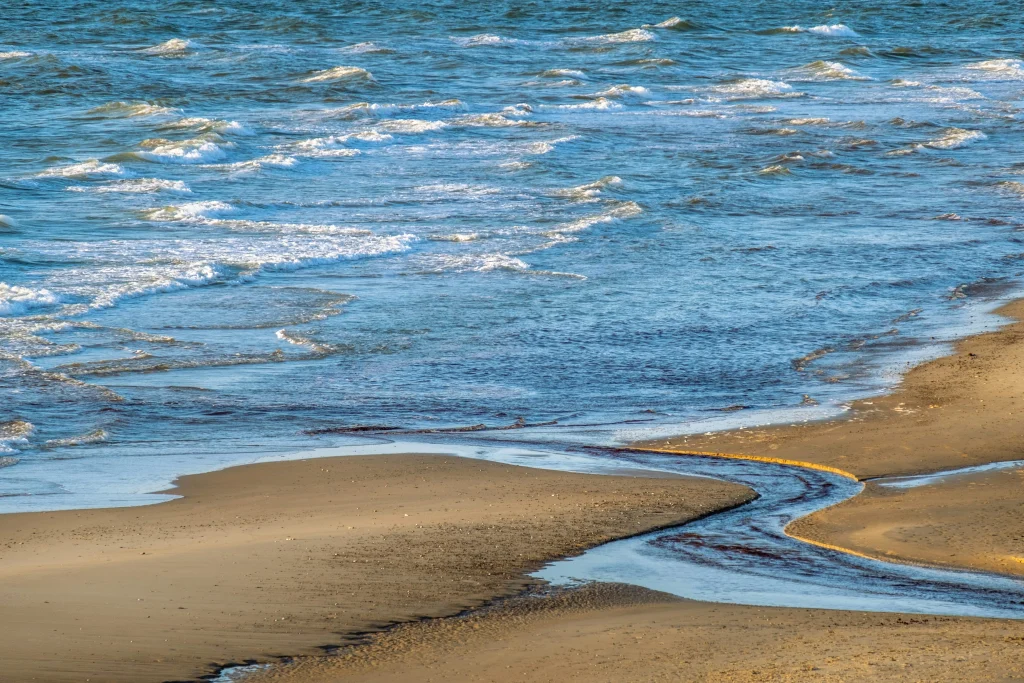 A beach scene with waves moving toward a golden brown sandy beach